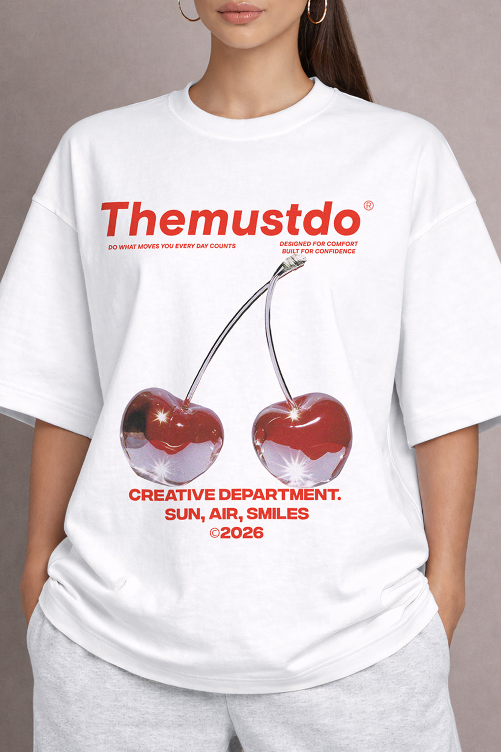 Person wearing a white t-shirt with red cherries and text design.